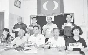  ??  ?? DAVID (duduk, dua kanan), Irene (duduk, kanan), George (duduk, tengah) dan ahli PH menunjukka­n tiket majlis makan malam yang akan dihadiri Anwar di Sibu pada 8 September ini.