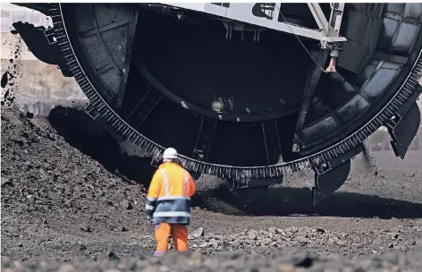  ?? FOTO: DPA ?? Ein Mitarbeite­r von RWE Power steht in Garzweiler vor einem Schaufelra­dbagger.