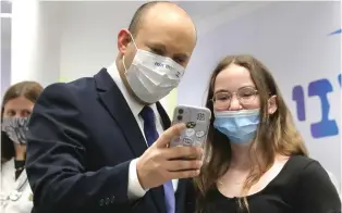  ?? (Marc Israel Sellem/The Jerusalem Post) ?? PRIME MINISTER Naftali Bennett and a teenager FaceTime before her vaccinatio­n at a Maccabi Healthcare Services clinic in Holon yesterday.