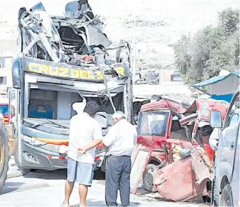  ?? — AFP photo ?? Men look at a a double-decker bus that crashed into parked cards on the Pan American Highway in the Arequipa region, southern Peru.