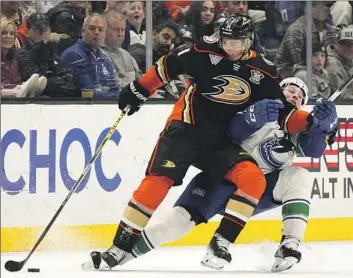  ?? Mark J. Terrill Associated Press ?? THE DUCKS’ Isac Lundestrom, left, tries to control the puck as he holds off the Canucks’ Brock Boeser.