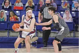  ??  ?? Gonzaga forward Drew Timme, left, works against Santa Clara forward Guglielmo Caruso last week in Spokane, Wash., in front of cutouts of fans.