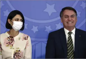  ?? ERALDO PERES — THE ASSOCIATED PRESS ?? Brazil’s President Jair Bolsonaro smiles sitting next to his wife, Michelle Bolsonaro, wearing a protective face mask, during the swearing-in ceremony of his new justice minister on Wednesday.