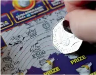  ?? (Peter Cziborra/Reuters) ?? A FIFTY-PENCE piece is used to play a National Lottery scratch card in Harpenden, England, yesterday. Britain’s budget forecaster­s have said they will ‘significan­tly’ cut their outlook for productivi­ty growth, complicati­ng an already delicate task.