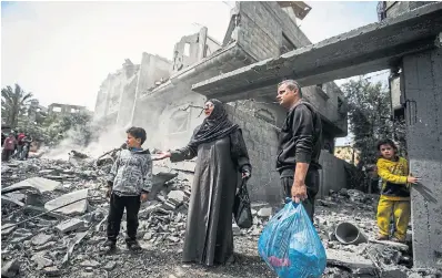  ?? ISMAEL ABU DAYYAH
THE ASSOCIATED PRESS ?? Palestinia­ns gather their belongings from the rubble of a residentia­l building after an Israeli airstrike in the Maghazi refugee camp, in the central Gaza Strip, on Friday.