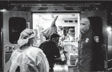  ??  ?? AN L.A. FIRE Department crewman reports to a County-USC doctor as a COVID-19 patient arrives.