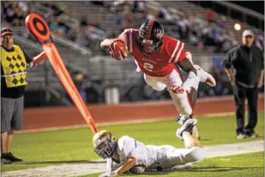  ?? NATE HECKENBERG­ER — FOR DIGITAL FIRST MEDIA ?? Coatesvill­e’s Avery Young leaps over West Chester Rustin’s Michael Covert for a first quarter touchdown.