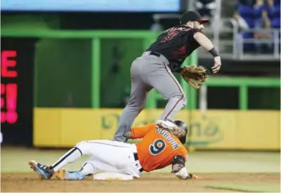  ??  ?? MIAMI: Arizona Diamondbac­ks second baseman Daniel Descalso (3) leaps over Miami Marlins’ Dee Gordon (9) after tagging the base for an out as he attempts a double play during the eighth inning of a baseball game, in Miami. — AP