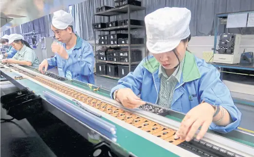  ?? REUTERS ?? Employees work on a production line of mobile gaming controller­s for U.S. company T2M at a factory in Dongguan, Guangdong province, China.