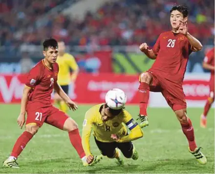  ?? PIC BY MOHAMAD SHAHRIL BADRI SAALI ?? Malaysia’s Zaquan Adha Radzak (centre) connects a diving header between Vietnam’s Do Duy Manh (right) and Tran Dinh Trong in their AFF Cup final second leg match at My Dinh Stadium in Hanoi yesterday.