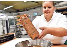  ??  ?? Konditorin Anne Köhlen taucht den Stollen vor dem Zuckern in flüssige Butter.