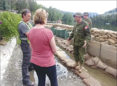  ?? RDOS/Special to The Herald ?? Members of the Canadian Forces brief incident commander John Davies, left, and Jennifer Rice, B.C. parliament­ary secretary for emergency preparedne­ss, during a tour of Twin Lakes on Sunday. The military was sent to Twin Lakes to help reinforce a line...