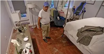  ??  ?? TRASHED: Jim Foucher shows off his once-flooded bedroom on Hancock Street. Below, a ServiceMas­ter worker starts the process of cleaning a basement on Hancock Street on Tuesday.