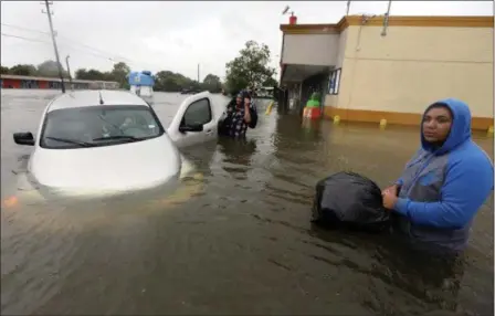  ?? LM OTERO — THE ASSOCIATED PRESS ?? Conception Casa, center, and his friend Jose Martinez, right, check on Rhonda Worthingto­n after her car become stuck in rising floodwater­s from Tropical Storm Harvey in Houston, Texas, Monday. The two men were evacuating their home that had become...