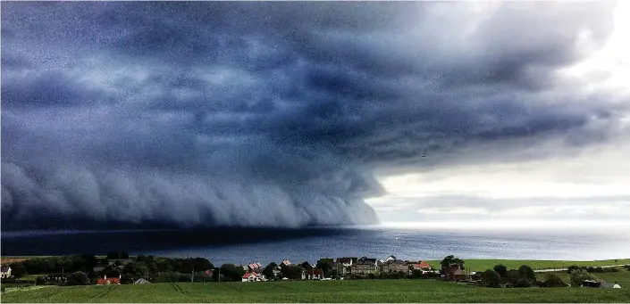  ??  ?? Storm brewing: The menacing wall of cloud towered over Burnmouth and dwarfed a fishing boat that was trying to get back to harbour before the weather broke