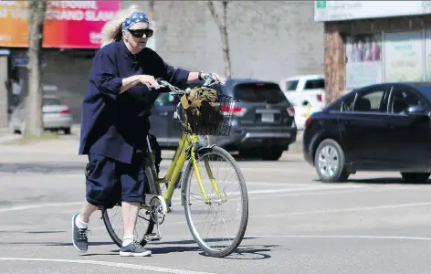  ?? MICHELLE BERG ?? A cyclist walks her bike across the street downtown. Organizers of Bike to Work YXE are hoping to see many more bikes out this week.