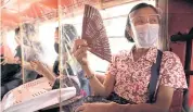  ??  ?? Jeepney passengers separated by plastic barriers wear face masks to guard against Covid-19 in Quezon City, Metro Manila.