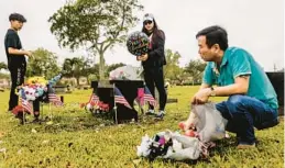  ?? SCOTT MCINTYRE/THE NEW YORK TIMES ?? Linda Zhang, her husband, Kong Feng Wang, and their son Jason Wang, 17, decorate Peter Wang’s gravesite on Nov. 9.