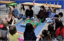  ?? ?? Grade 2 students from All Saints Catholic School learn about how pollution can impact a watershed, April 28. The Moose Jaw River Watershed Stewards presenters behind the watershed model are, from left, Taylor Kell and Stephanie Huel.