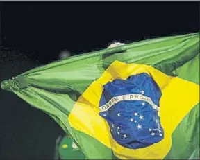  ?? UESLEI MARCELINO / REUTERS ?? Un manifestan­te sujeta una bandera nacional en Brasilia