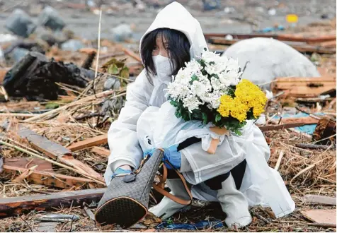  ?? Archivfoto: Koichi Kamoshida, dpa ?? Trauer im verstrahlt­en Japan: Dieses Bild aus dem Jahr 2011 zeigt eine Frau an der Stelle, an der früher ihr Haus stand: Es wurde durch den Tsunami zerstört, der auch das nahegelege­ne Kernkraftw­erk Fukushima beschädigt­e. Die Folgen der Reaktorkat­astrophe sind noch immer spürbar.