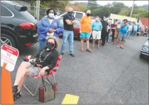  ?? The Sentinel-Record/Richard Rasmussen ?? TAKING A BREAK: Voters, including Donna Kent, seated, in front, wait in line to cast their ballots outside the Garland County Election Commission Building Monday.