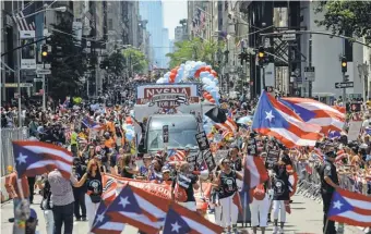  ?? STEPHANIE KEITH, GETTY IMAGES ?? Tens of thousands of people march up Fifth Avenue in the annual Puerto Rican Day Parade in New York City on Sunday even as residents of Puerto Rico voted on the status of the island.