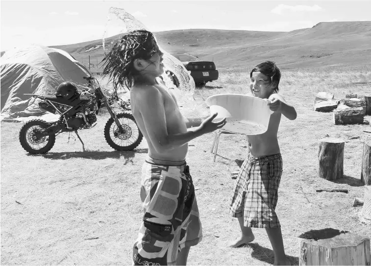  ?? LORRAINE HJALTE/ POSTMEDIA NEWS ?? Isaac Littlechil­d, 11, gets splashed by water thrown his way by brother Matthew, 8. The Littlechil­d family and others from Sitsika Nation east of Calgary lost their homes to flooding in June.