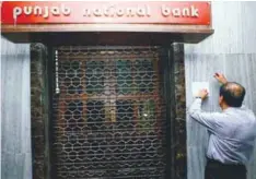  ??  ?? A man tries to remove a notice pasted on the wall of a Punjab National Bank branch after it was sealed by India's federal police in Mumbai, India, yesterday.