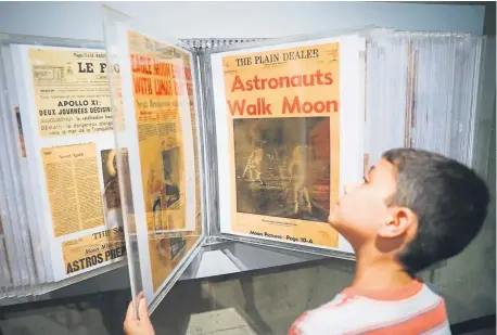  ?? John Minchillo, The Associated Press ?? Ethan Reynolds browses a display of newspaper pages announcing the first moon landing at the Armstrong Air & Space Museum on Saturday in Wapakoneta, Ohio. Saturday was the 50th anniversar­y of Apollo 11’s arrival on the moon.