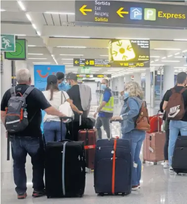  ??  ?? Viajeros reciben informació­n en el aeropuerto de Palma de Mallorca.