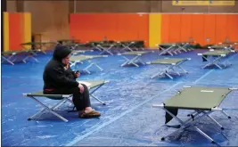  ?? JOSIE LEPE/ FOR BAY AREA NEWS GROUP ?? Coyote Creek unhoused resident Jerusha Kneib, 41, sits on a cot for the night as she starts to watch a show on her phone after arriving to the Red Cross evacuation shelter at Seven Trees Community Center in San Jose on Wednesday.