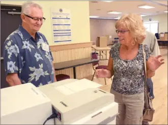  ?? GARY NYLANDER/The Daily Courier ?? Elections official Michael Syvenky looks on as Kathy Chappell casts her ballot Tuesday at the Westbank Lions Community Centre during an advance poll on the West Kelowna Civic Centre project, which includes a new city hall. General voting in the...