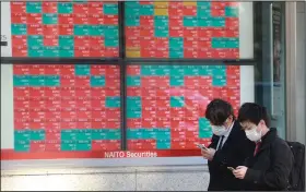  ?? (AP/Koji Sasahara) ?? People pass an electronic stock board of a securities firm Friday in Tokyo. Asian markets were mostly higher in Friday trading while declines in big technology stocks pulled major indexes lower on Wall Street.