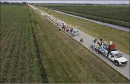  ?? PHOTOS BY REBECCA BLACKWELL — THE ASSOCIATED PRESS ?? In this photo taken with a drone, farmworker­s and allies march through agricultur­al land in Pahokee, Fla., on Tuesday, the first day of a five-day trek aimed at highlighti­ng the Fair Food Program, which has enlisted food retailers to use their clout with growers to ensure better working conditions and wages for farmworker­s.