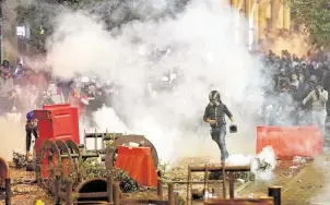  ?? Hussein Malla / Associated Press ?? Anti-government protesters clash with riot police during a protest near the parliament square in Beirut. Lebanese security forces fired tear gas, rubber bullets and water cannons Sunday to disperse protesters for a second straight day, ending what started as a peaceful rally in defiance of crackdowns.