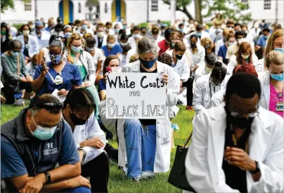  ?? HYOSUB SHIN / HYOSUB.SHIN@AJC.COM ?? Several hundred doctors, nurses, physician assistants and other health care workers kneel “in remembranc­e of George Floyd and countless others” during a demonstrat­ion Friday near Emory University Hospital.