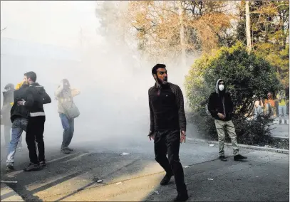  ??  ?? The Associated Press Students attend a protest Saturday inside Tehran University and deal with a smoke grenade thrown by police in Tehran, Iran.