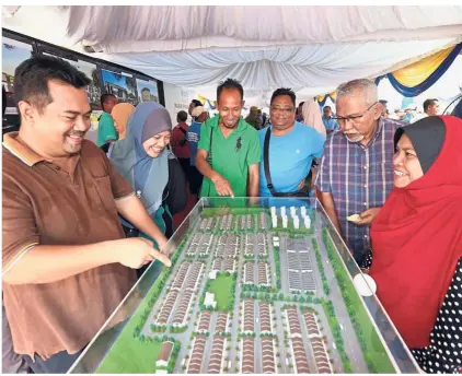  ??  ?? For the people: Members of the public looking at the scale of the Johor Affordable Homes scheme (RMMJ) in Bandar Penawar, Pengerang in Johor. (Left pic) Mohamed Khaled (centre), Johor Housing and Local Authority Committee chairman Datuk Md Jais Sarday...