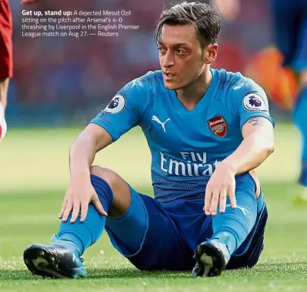  ?? — Reuters ?? Get up, stand up: A dejected Mesut Ozil sitting on the pitch after Arsenal’s 4- 0 thrashing by Liverpool in the English Premier League match on Aug 27.