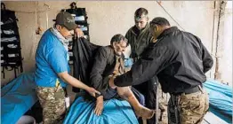  ?? MARCUS YAM/LOS ANGELES TIMES ?? Jadwaa Hamad gets help from Maj. Tarek Gazali, right, and Thomas Ordway, second from right, at field clinic.