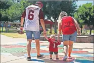  ?? [PAXSON HAWS/ THE OKLAHOMAN] ?? Everton Baker House hold hands with Derek and Karis House as he walks across Yukon City Park on July 19.