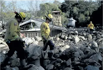  ?? JUSTIN SULLIVAN/GETTY IMAGES ?? Firefighte­rs search for people trapped after mudslides in Montecito, Calif. At least 17 people have died after torrential rains unleashed mudslides on Tuesday.