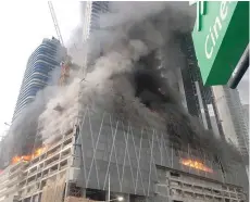  ?? — Reuters ?? A fire is seen at a tower under constructi­on in Dubai’s Downtown district on Sunday.