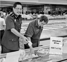  ??  ?? Abdul Hafiz (left) checks a food item at an outlet in Sibu Central Market in this file photo.