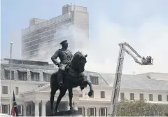  ?? REUTERS ?? A statue of Louis Botha, former prime minister of South Africa, is seen in front of the parliament where a fire broke out in Cape Town on Sunday.