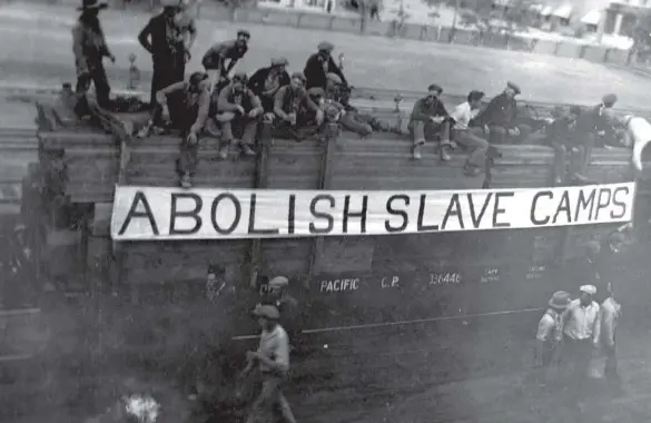  ??  ?? Unemployed men on the On to Ottawa Trek display a sign with one of their demands. The Department of National Defence relief camps were called “slave camps” by those who worked in them for twenty cents a day.