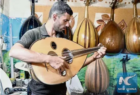  ?? — Xinhua ?? Music to the ears: Samir playing a traditiona­l lute in his workshop for tourists at Rasheed Street in downtown Baghdad, Iraq.