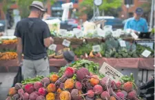  ?? Gabriel Scarlett, Special to The Denver Post ?? Shoppers at the Cure Organic Farm tent at the Union Station Farmers Market on July 15, 2017. For the 2020 season, farmers markets are moving to virtual sales in response to the coronaviru­s pandemic.