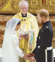  ?? AFP ?? Prince Harry and Meghan Markle stand hand in hand before Archbishop of Canterbury Justin Welby during their wedding ceremony in St. George’s Chapel at Windsor Castle.